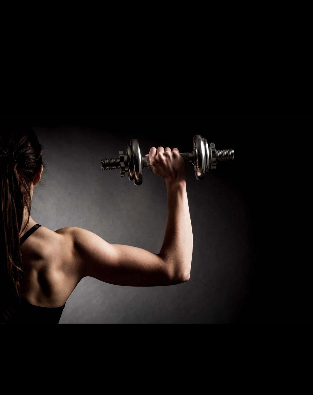 A woman curling a dumbbell in low light